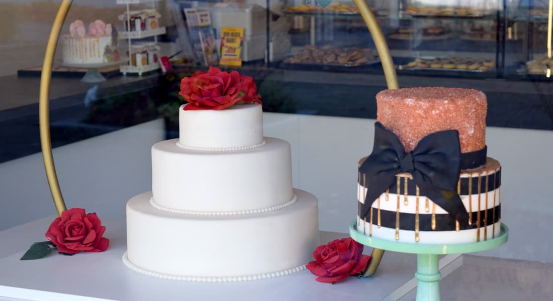 Schaufensterdekoration mit weißer Hochzeitstorte und roten Rosen