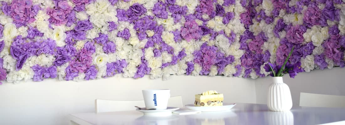 Sitzecke mit Blumenwand, Kaffee und Kuchenstück